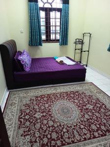 a bedroom with a purple bed and a rug at Jiddah Homestay in Tumpat