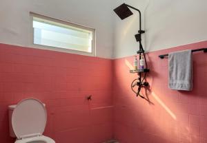 a bathroom with pink tiles and a window and a toilet at Decasa Female House in Malang