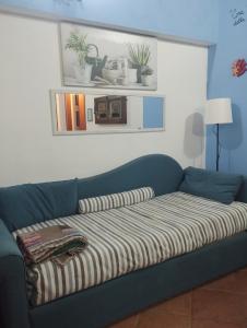 a blue couch with a striped blanket on it at La casetta del pescatore - Le case di Bettina in Torrenova