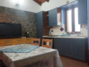 a kitchen with blue cabinets and a table and a tv at La casetta del pescatore - Le case di Bettina in Torrenova