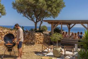 a man standing next to a grill with a group of people at Villa Bianca in LʼÎle-Rousse