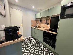 a kitchen with a black and white tiled floor at La Cabine ménage et linge inclus in Dieppe