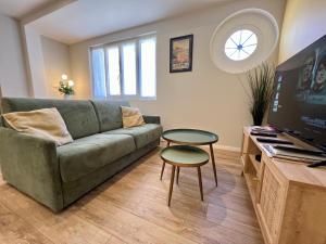 a living room with a green couch and a table at La Cabine ménage et linge inclus in Dieppe