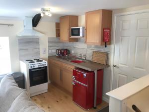 a small kitchen with a red stove and microwave at Brewery Lodge in Blakeney