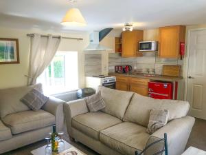 a living room with two couches and a kitchen at Brewery Lodge in Blakeney