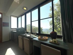 a room with a table with chairs and large windows at Shakti, Abdelli guesthouse in Batroûn