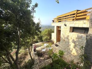 a stone house on a hill with trees and flowers at Shakti, Abdelli guesthouse in Batroûn