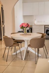 a white table with chairs and a vase of pink flowers at Aphrodite Breeze Paphos Gardens in Paphos