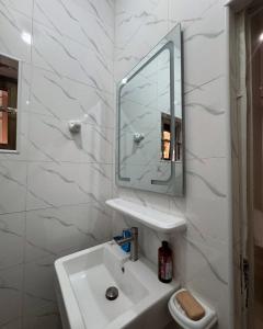 a white bathroom with a sink and a mirror at Havenstay in Yaoundé
