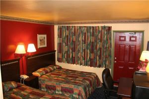 a hotel room with a bed and a desk and a bed and a bed sqor at Plaza Travel Inn in Clewiston