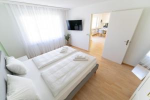 a white bedroom with a large bed and a living room at Cozy Swiss Apartment - City & Mountain view in Interlaken
