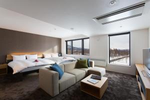 Habitación de hotel con cama y sofá en Always Niseko, en Niseko