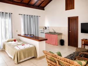 a living room with a table and a kitchen at Arraial Praia Hotel Pousada in Arraial d'Ajuda