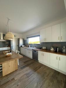 a large kitchen with white cabinets and a wooden floor at Monte da Fonte in Odemira