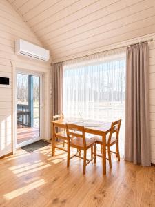 a dining room with a table and a large window at Atpūtas mājas Leiksnīte in Vaikulāni