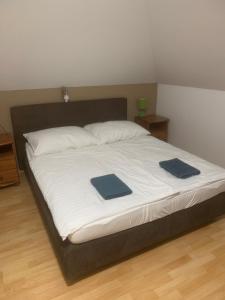 a large bed with two blue pillows on it at Zátonyi Csárda Panzió in Dunasziget