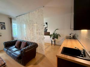 a living room with a leather couch in a kitchen at Richie Apartment near Aquapark in Prague