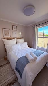 a bedroom with a large white bed with a window at Sunset Beach Self-Catering in Marina da Gama