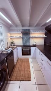 a kitchen with white cabinets and a dishwasher at Sunset Beach Self-Catering in Marina da Gama