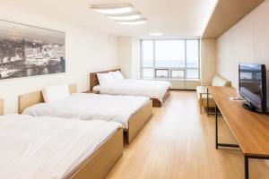 two beds in a room with a desk and a tv at Incheon Airport Egarak Residence in Incheon