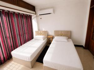 two beds in a room with red curtains at Nile View Studio Aswan in Aswan