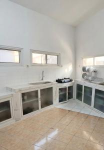 a white kitchen with a sink and windows at Decasa Female House in Malang +34 photos