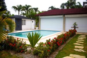 a swimming pool in front of a house with flowers at Villa La Dueña Perfect Escape in Las Terrenas
