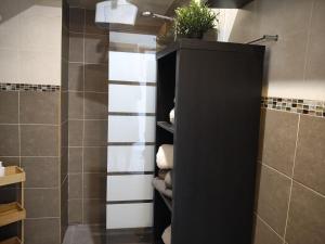 a bathroom with a shower with a black cabinet with towels at Casa Verão Azul in Monte Gordo