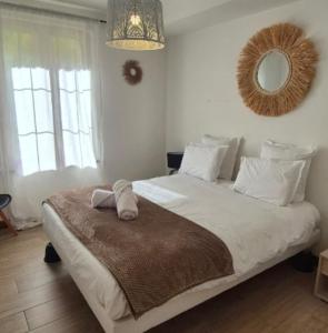 a bedroom with a large white bed with a mirror at havre de paix a la Sologne in Veilleins