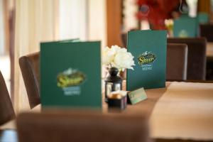 a table with two green boxes and a vase of flowers at Hotel Sjever in Šavnik