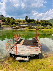 a boat sitting on the water with a wooden deck at Apartmani SEEBLICK in Konjic