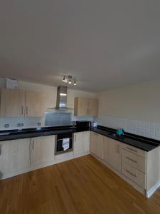 an empty kitchen with black counter tops and wooden cabinets at Beautiful 2 Bedroom - Woolwich in Woolwich +9 photos