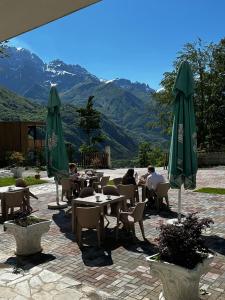 a group of people sitting at tables with umbrellas at Trojet e Mija in Theth