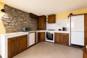 a kitchen with wooden cabinets and a stone wall at The Old Barn by Roby in Saint Vincent