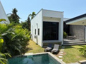a house with a swimming pool next to a backyard at Noir Blanc Modern Villa in Ko Phangan