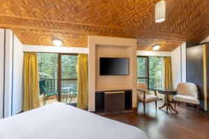 a bedroom with a bed and a flat screen tv at Radisson Golf Resort Pahalgam in Pahalgām