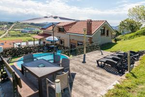 a patio with a table and chairs and a house at La Centinela en Costa Quebrada in Miengo