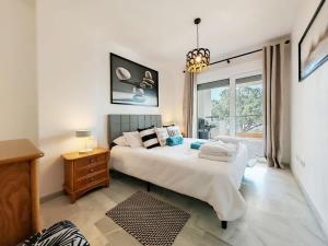 a bedroom with a large white bed and a window at Sea View - Pool view - Beach Front - 25 meter to beach in Málaga