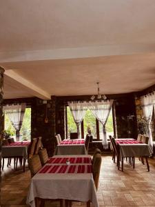 a dining room with tables and chairs and windows at Trojet e Mija in Theth