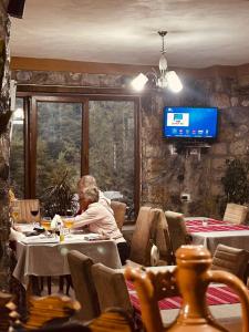 a man sitting at a table in a restaurant at Trojet e Mija in Theth