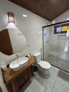 a bathroom with a sink and a toilet and a mirror at Chalé samambaia in Resende