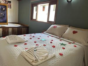 a bed with a white bedspread with flowers on it at Chalé samambaia in Resende