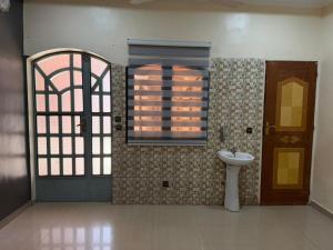 a bathroom with a sink and a window and a door at Jfk3 in Ouagadougou