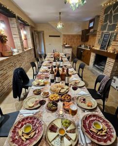 a long table with plates of food and bottles of wine at MEQUEDO el ESPOLON in Alcañiz