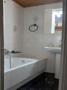 a bathroom with a bath tub and a sink at Τα σπίτια στα Λειβάδια - Γαρδένια in Vrakhnós