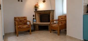 a living room with two chairs and a fireplace at Τα σπίτια στα Λειβάδια - Γαρδένια in Vrakhnós