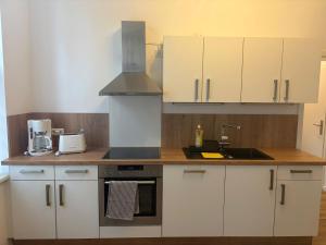 a kitchen with white cabinets and a sink at Ferienwohnung Franka in Sonneberg +6 photos
