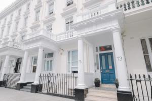 a white building with a blue door on a street at Astor Victoria Hostel in London