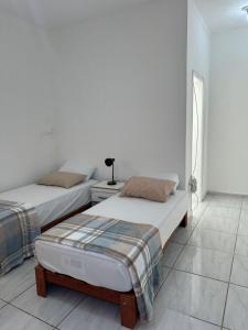 two twin beds in a white room with a window at Apartamento Tio Du in Sorocaba