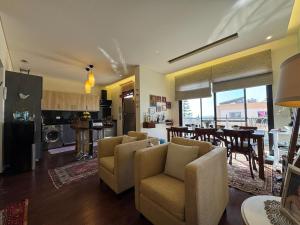a living room with chairs and a table and a kitchen at Batroun Escape, 2BR, 24-7 elect, beach view! in Batroûn
